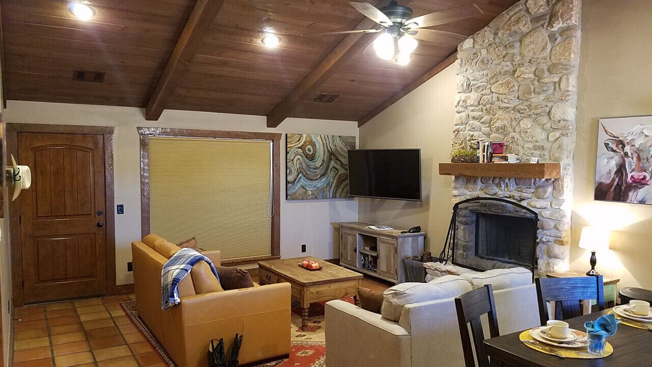 A cozy living room with a stone fireplace, a television, and comfortable seating.