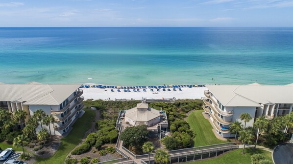 An aerial view of a beachfront hotel with a beach, ocean, and multiple buildings.