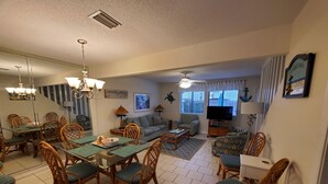A spacious living room with a dining area, a sofa, a television, and a ceiling fan. - Paradise On The Beach With Crystal Clear Water & Gulf Front Complex--2 BR Suites (Navarre)