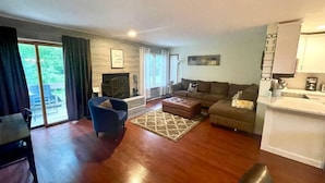 A living room with a sofa, ottoman, and a dining area with a table and chairs.