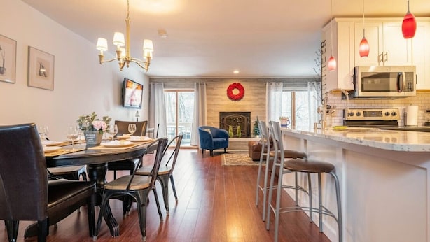 A modern kitchen with a microwave, oven, and bar area. There is a dining area with a table set for four.