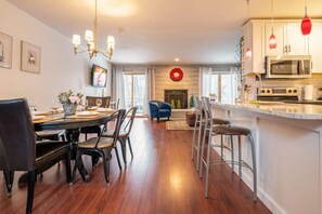 A modern kitchen with a microwave, oven, and bar area. There is a dining area with a table set for four.
