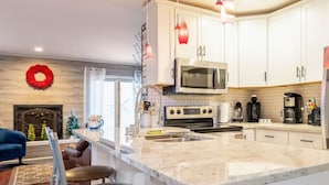 A modern kitchen with white cabinets, a large island with bar stools, a microwave, stove, and coffee maker.