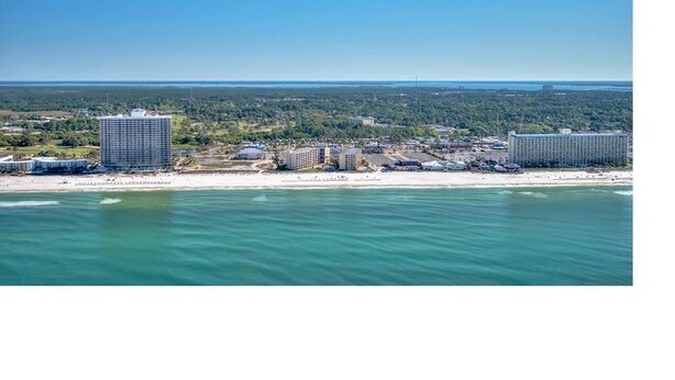 An aerial view of a coastal area with two large hotels, a beach, and a forested landscape. - Beautiful Beachfront Studio with Beach Chairs for 2 (Panama City Beach)