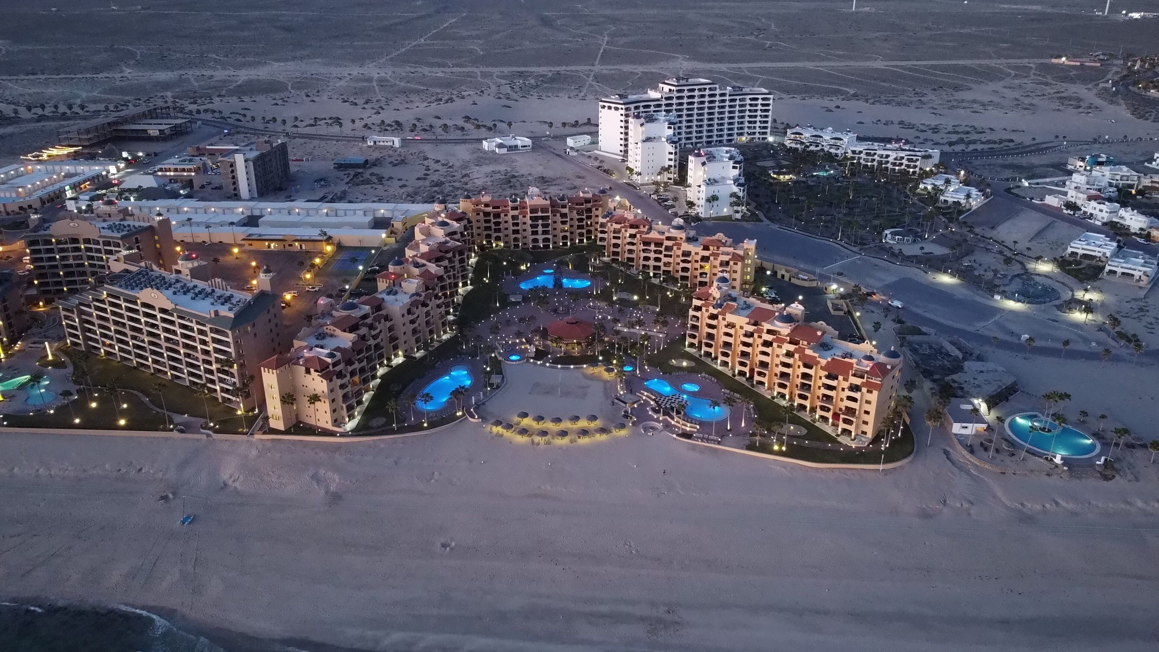 Un complexe hôtelier comprenant plusieurs bâtiments, des piscines et une plage.