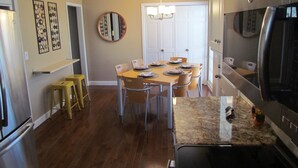 A kitchen with a granite countertop, stainless steel appliances, and a dining area with a table set for four.