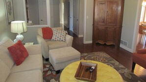 A living room with a sofa, ottoman, and a wooden cabinet.