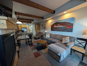 A modern living room with a sofa, coffee table, and dining area.