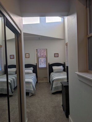 Ein Schlafzimmer mit zwei Betten, einem Fenster mit Jalousien und einer Deckenleuchte.