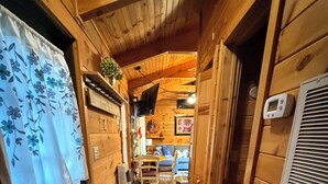 A wooden interior with a hallway leading to a living area, a television mounted on the wall, and a thermostat on the wall. - WATER FRONT CABIN FOR COUPLES! (Butler)