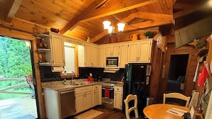 A wooden cabin interior with a kitchen, dining area, and a view of the outdoors. - WATER FRONT CABIN FOR COUPLES! (Butler)