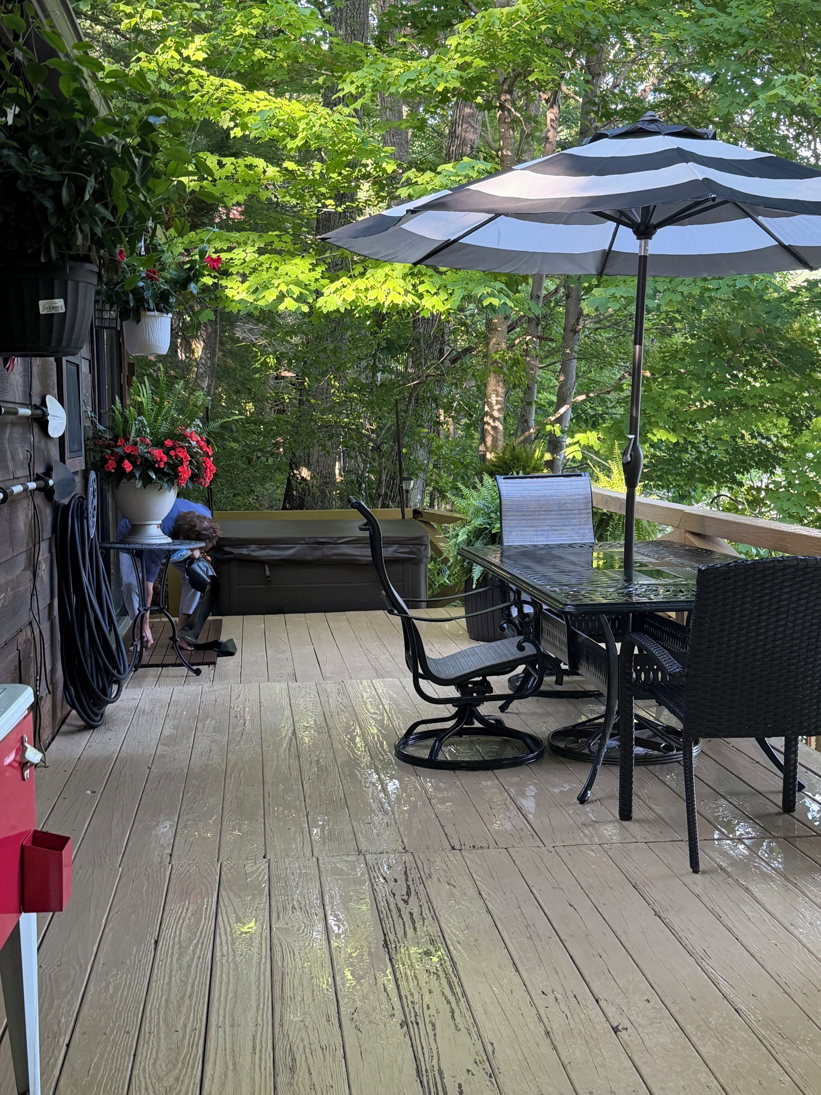 A wooden deck with a table and chairs, a large umbrella, and potted plants.