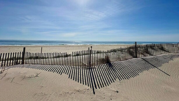 Een strand met een houten hek en een heldere lucht.