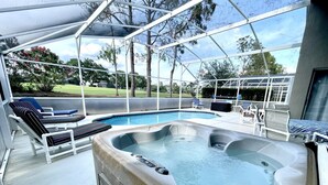 Un área de piscina exterior con jacuzzi, sillas de descanso y un porche cubierto.