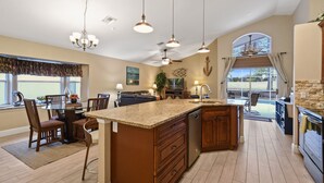 Una cocina amplia con una isla central, iluminación colgante y vistas al exterior.