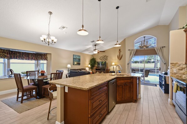 A spacious kitchen with a central island, pendant lighting, and a view to the outside.