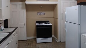A compact kitchen with white cabinets, a gas stove, a refrigerator, and a wall-mounted sign that reads "EAT drink". - CHARMING-Historic,Trinity University,Pearl Brewery, ONLY 3 miles to DT&Riverwalk (San Antonio)
