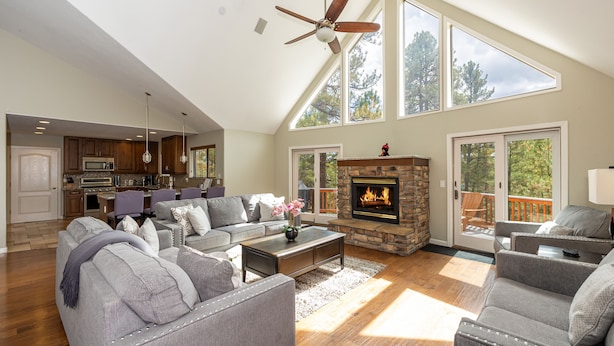 A spacious living room with a fireplace, a dining area, and a kitchen. - Holland Home - Luxury home w/ Forest Views, AC & Hot Tub! (Flagstaff)