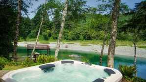 Ein Whirlpool, umgeben von einer natürlichen Landschaft mit Fluss und Bäumen.