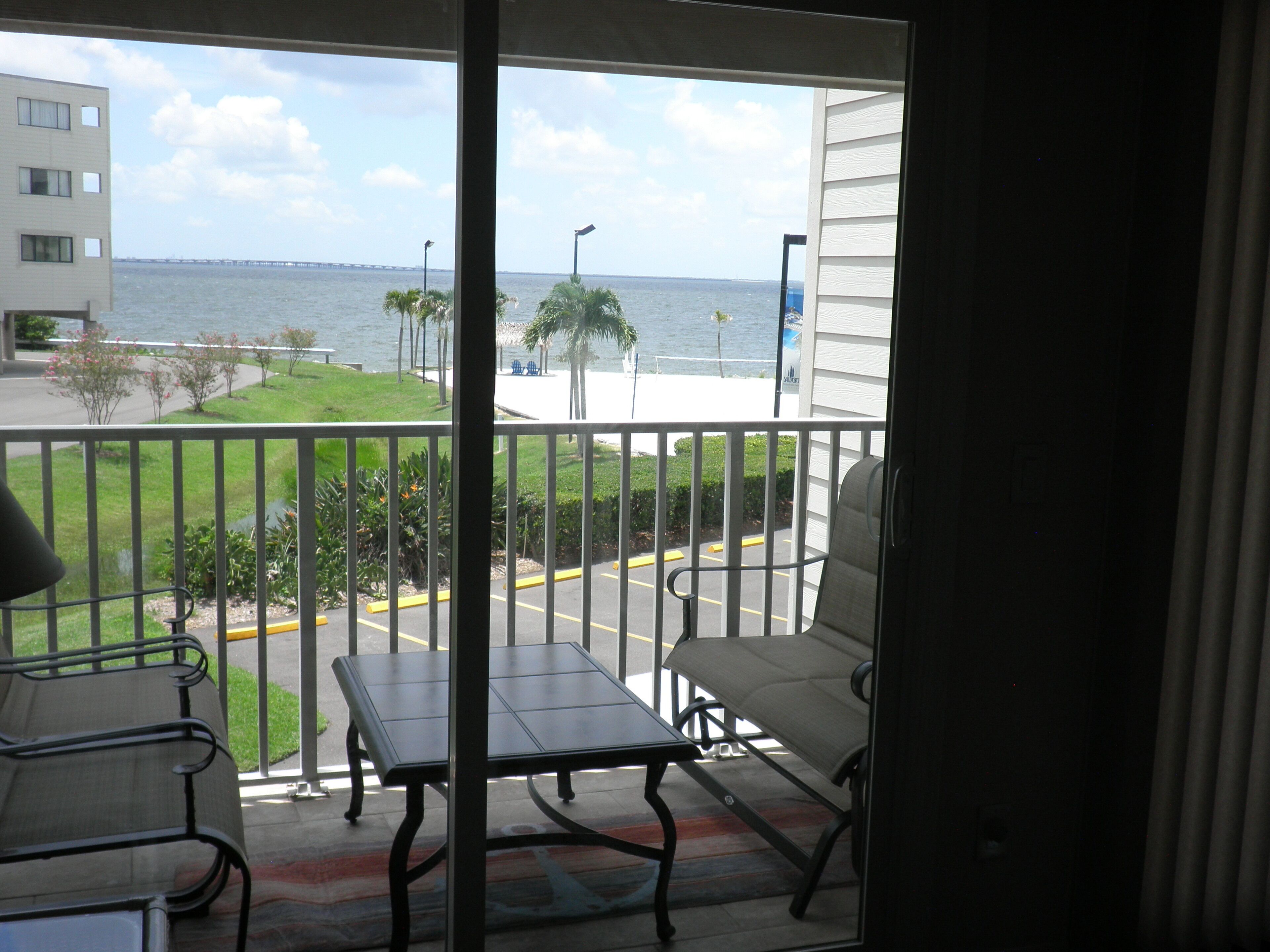 A balcony with a view of the sea, a table, and two chairs.
