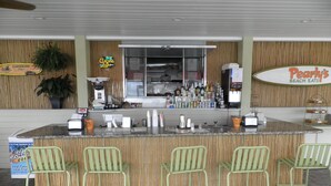 Een bar met een toonbank, barkrukken en diverse flessen.