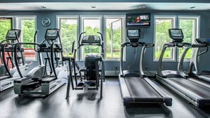Kuntosali, jossa on juoksumattoja, kuntopyöriä ja televisioruutu.
