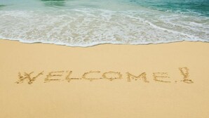Una spiaggia con la scritta 'WELCOME!' sulla sabbia.