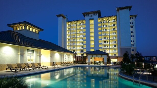 Un hotel con una grande piscina, diversi piani e un esterno ben illuminato.