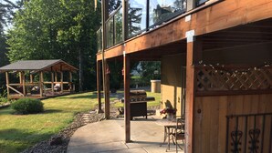 A covered patio area with a barbecue grill, seating, and a wooden deck.