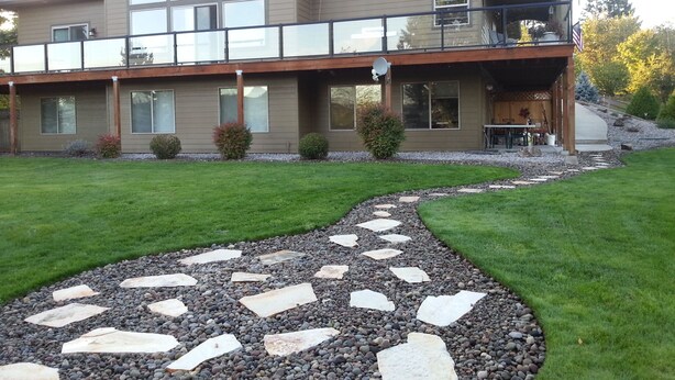 A two-story house with a covered patio, large windows, and a stone pathway leading to the entrance.