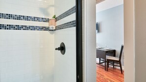 A room with white tiled walls, a black-framed door, and a dining area with a table and chairs. - Modern Studio in  Downtown Newberg - Suite #2 (Newberg)