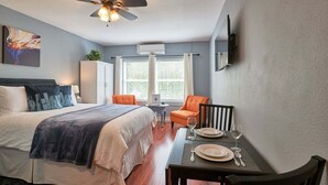 A bedroom with a bed, a dining table set with plates and glasses, a chair, and a ceiling fan. - Modern Studio in  Downtown Newberg - Suite #2 (Newberg)