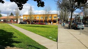 A building with a yellow facade, a parking lot, and a grassy area. - Modern Studio in  Downtown Newberg - Suite #2 (Newberg)