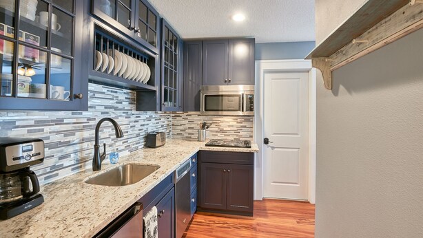 A modern kitchen with dark cabinets, a stainless steel microwave, a coffee maker, and a tiled backsplash. - Modern Studio in  Downtown Newberg - Suite #2 (Newberg)
