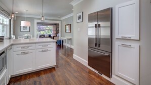 Une cuisine moderne avec des meubles blancs, des appareils électroménagers en acier inoxydable et un plancher en bois.