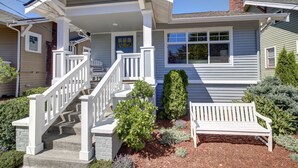 Une maison à deux étages avec un porche à l’avant, un escalier et un banc.