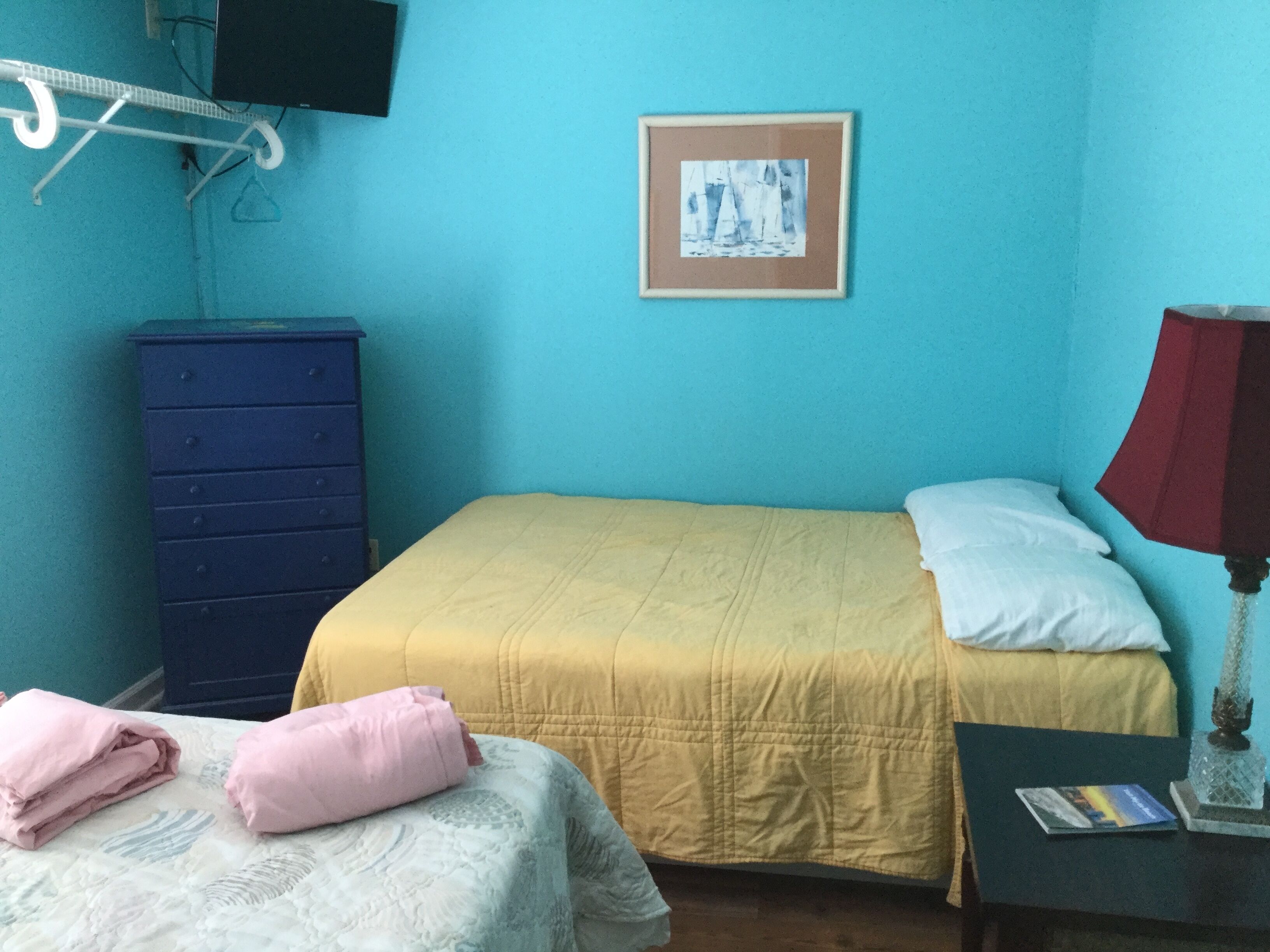 Una habitación con una cama, un aparador, una lámpara y un cuadro en la pared.