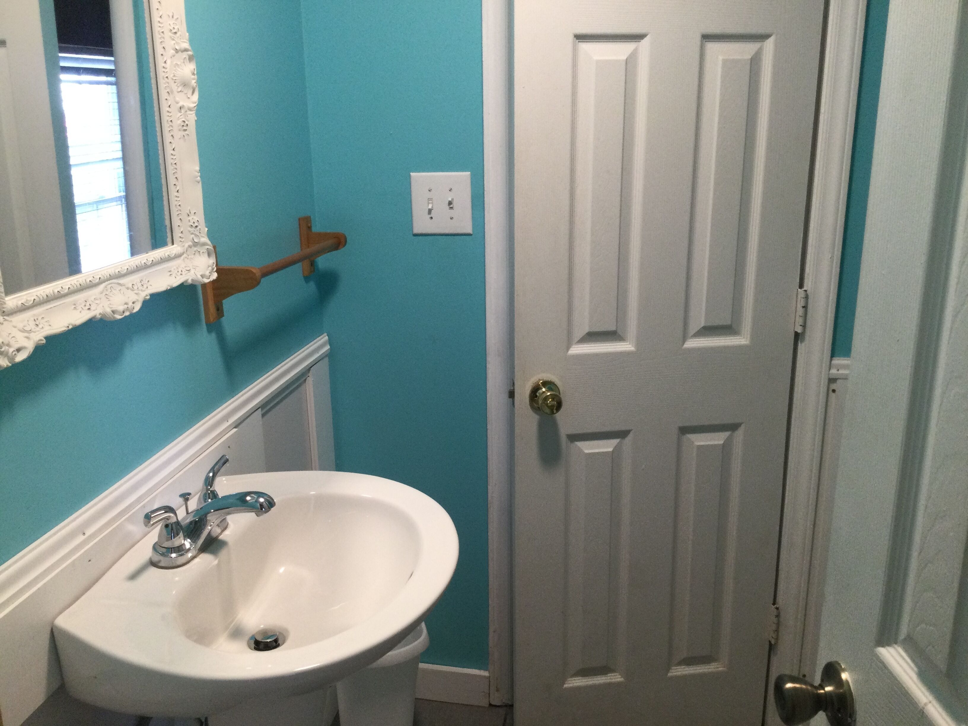 A bathroom with a white sink, a mirror, and a door.
