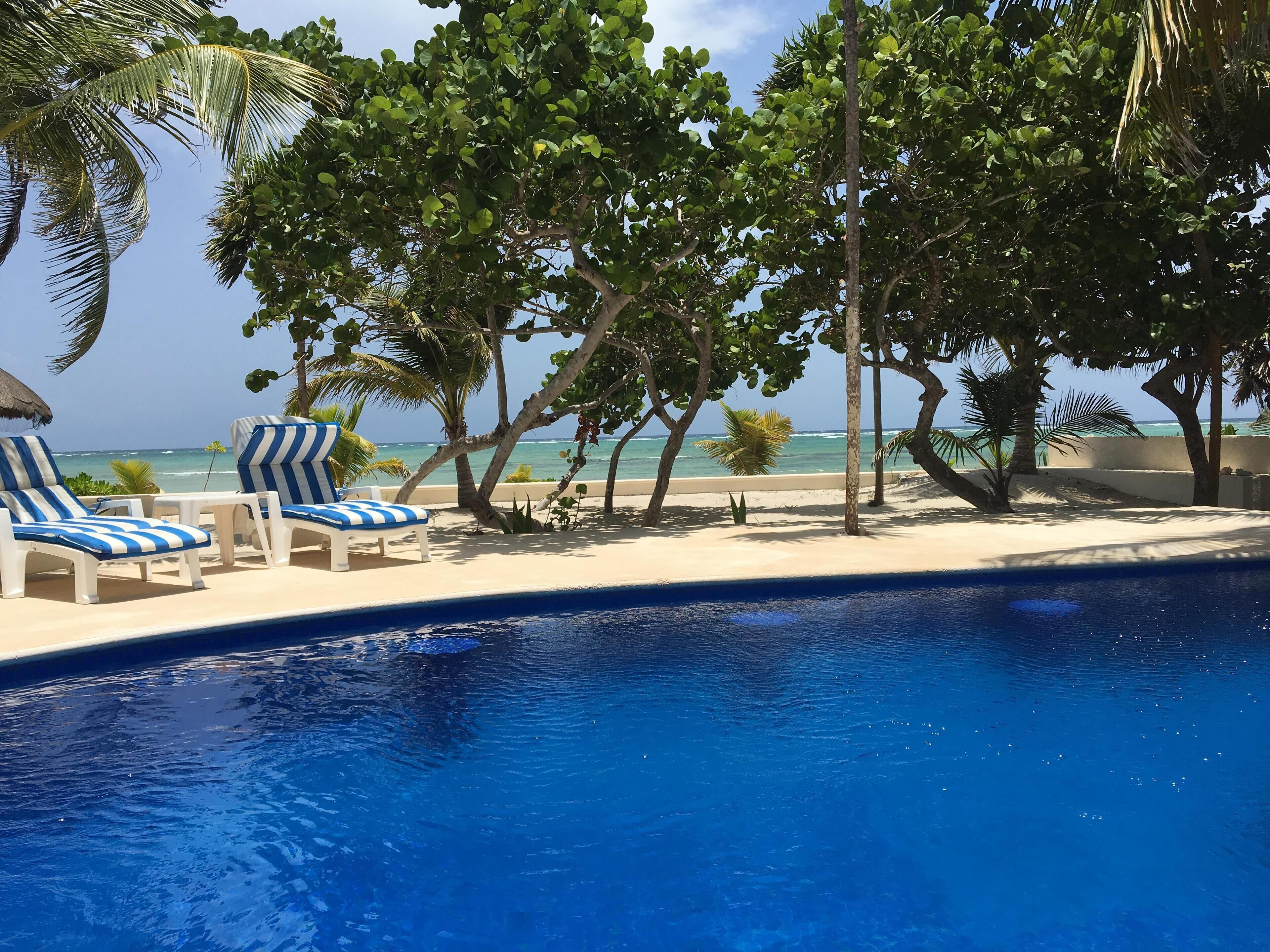 A poolside area with lounge chairs and a view of the ocean.