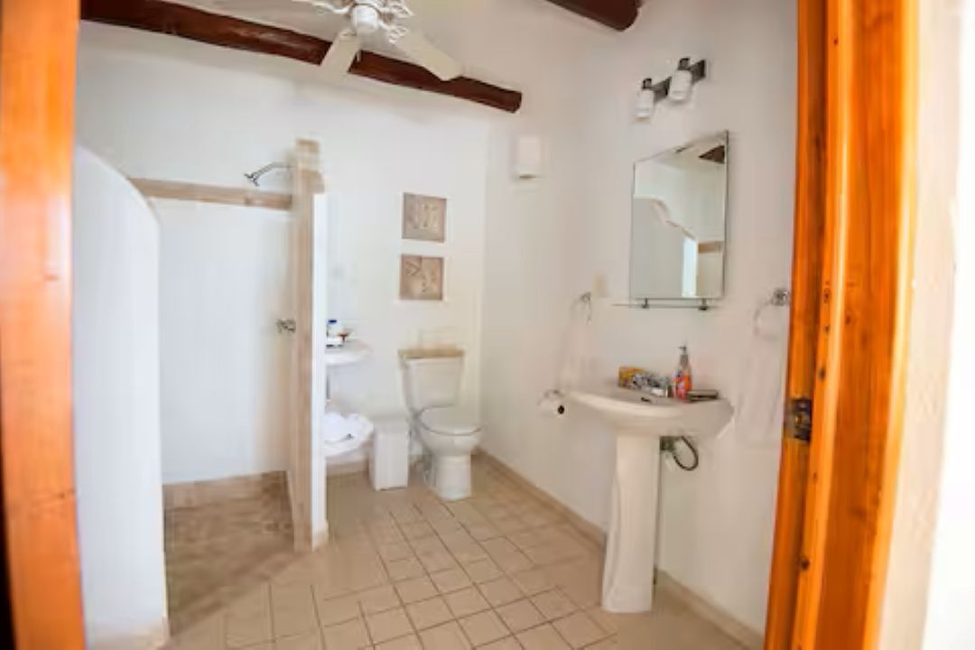 Un baño con inodoro, lavamanos y zona de ducha.