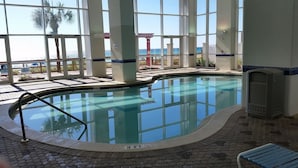 An indoor swimming pool with clear glass walls, a tiled floor, and a view of the ocean. - TOP FLOOR, GREAT VIEW, FRIENDLY PRICES! (Panama City Beach)