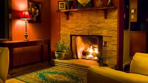 A cozy living room with a fireplace, a lamp, and a sofa. - Stunning, majestic, oceanfront location, with stunning view and air conditioning (Hilo)