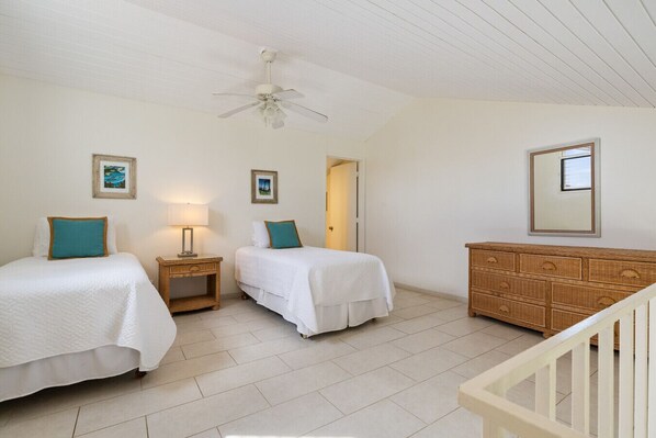 A bedroom with two beds, a nightstand, a dresser, and a ceiling fan.