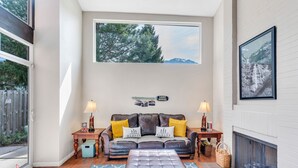 A cozy living room with a leather sofa, two lamps, a fireplace, and a large window overlooking trees. - Large Townhouse, 3Bd/3Ba, Near BYU Stadium/BYU  (Provo)