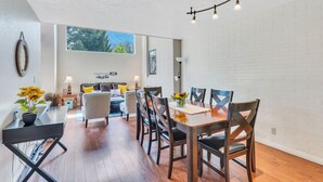 A dining area with a wooden table and chairs, a potted plant, and a view of the living room. - Large Townhouse, 3Bd/3Ba, Near BYU Stadium/BYU  (Provo)