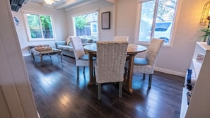 Un coin repas avec une table ronde et des chaises en osier, un canapé et une table basse agrémentée de paniers.