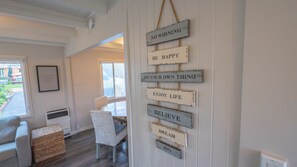 Et værelse med et skilt på væggen med motiverende citater, en fletstol, et lille bord og udsigt gennem et vindue.