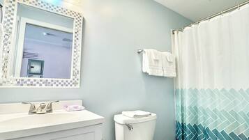 Ein Badezimmer mit Toilette, Waschbecken, Spiegel und Duschvorhang.