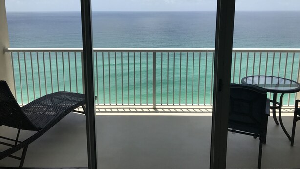 A balcony with a view of the ocean, a table, and two chairs. - JUST LISTED, OPEN CALENDAR, FRIENDLY PRICES (Panama City Beach)