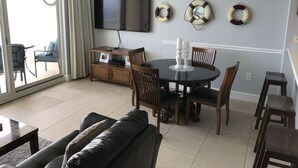 A living room with a TV, dining table, chairs, and a sofa. - JUST LISTED, OPEN CALENDAR, FRIENDLY PRICES (Panama City Beach)